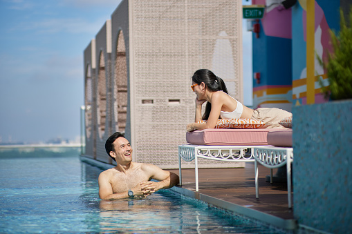 Asian couple enjoying and chatting by hotel pool