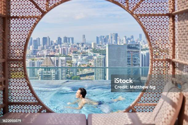 Attractive Asian Man Swimming And Doing Laps At Infinity Pool With City Skyline Stock Photo - Download Image Now
