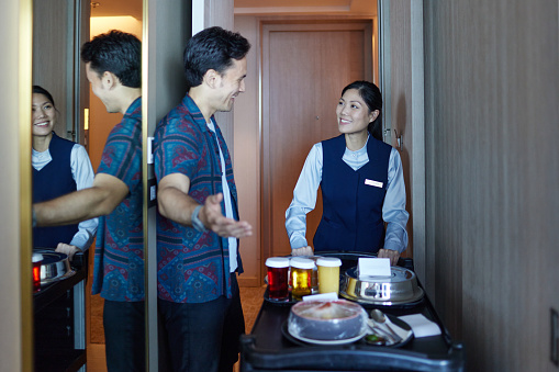 Asian hotel staff bringing room service to customer
