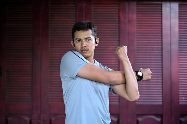 Fifteen year old teenage boy flexing his arm muscle, studio shot against a white background