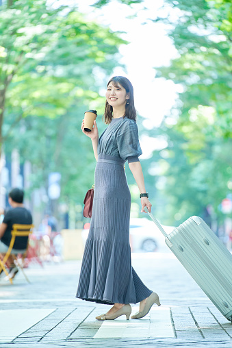 A woman walking in the city with a suitcase on fine day