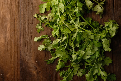 Coriander leaves on brown wooden table. Herb leaves are commonly used for seasoning. Coriandrum sativum