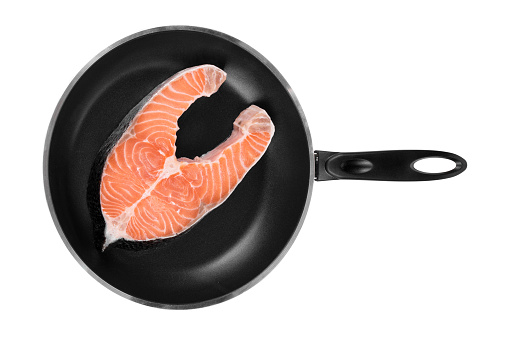 Salmon steak on a non-stick frying pan. Isolated on a white background. Close-up.