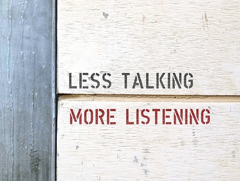 Line on wall separating two parts with text LESS TALKING MORE LISTENING,  to speak less and listen more , learn from peoples stories- stop talking too much and leave space for others to speak their voices