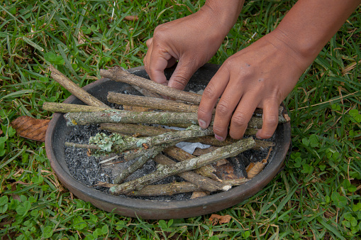 Person placing some dried tree sticks on a bowl to make a fire for an indigenous ritual. High quality photo