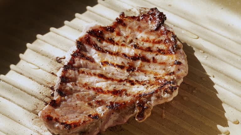 Pork steak turned over to the other side on a hot pan.