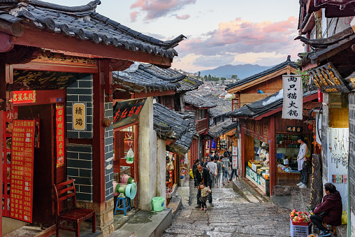 Lijiang, Yunnan Province, China - October 23, 2015: Awesome view of cozy narrow street of the Old Town of Lijiang at sunset. The ancient town is a popular tourist destination of Asia.