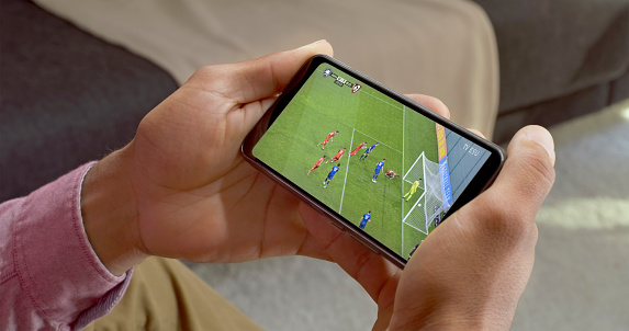 Close-up of man watching football sport on smart phone.