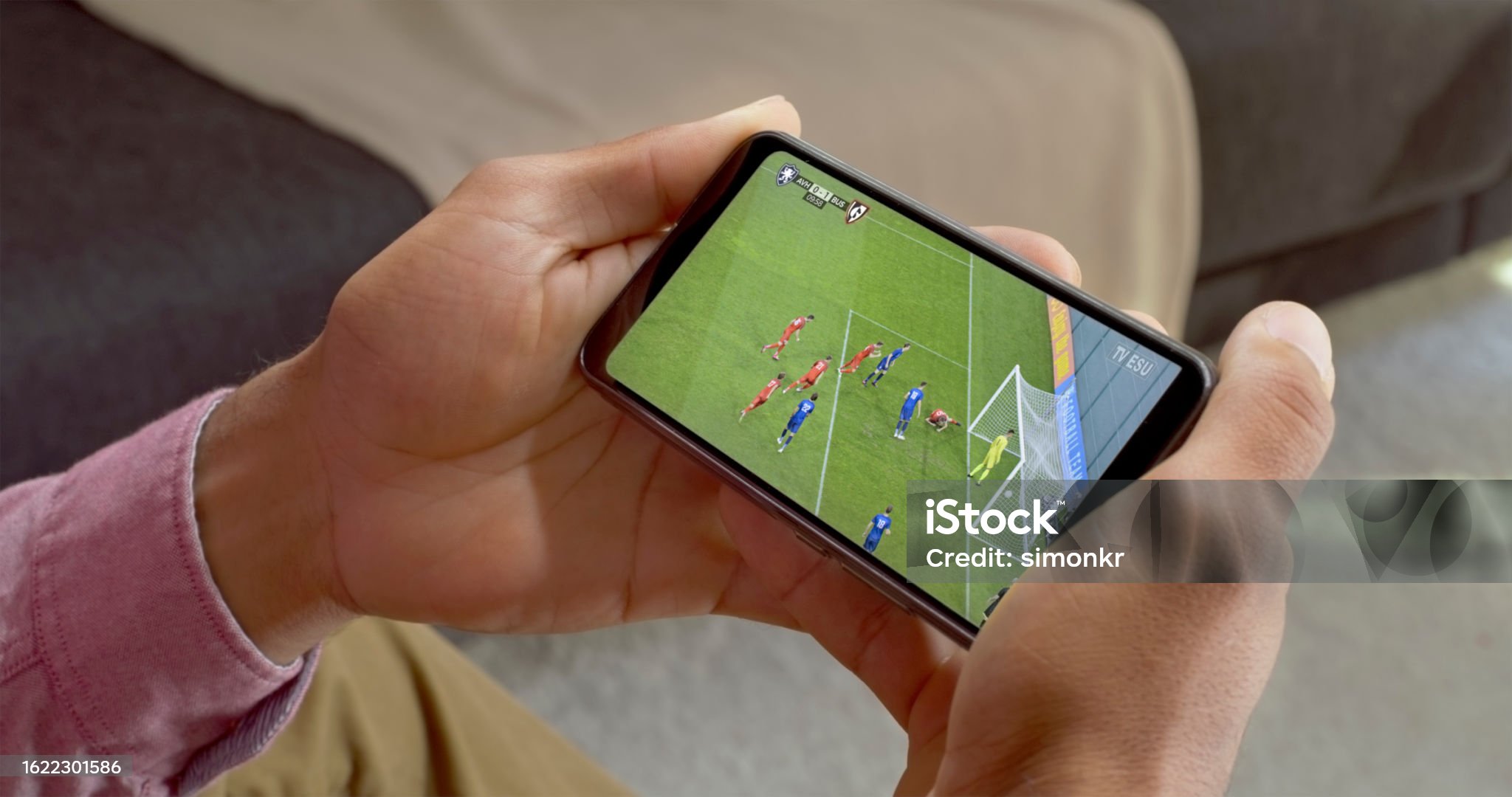 Tangan memegang smartphone menampilkan game FC Mobile