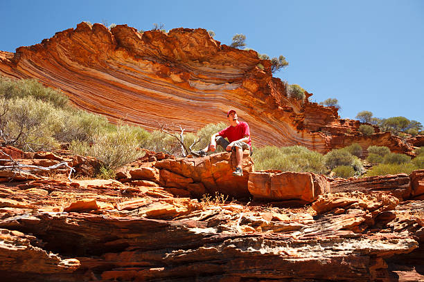 Man sitting bottom of colourful layered rock stock photo