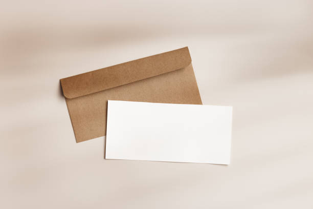 istock Blank paper card mock up and craft envelope on beige background. White empty letter or invitation on table, sunlight, beautiful shadow. Minimal modern lifestyle. Flat lay, top view, copy space. 1622330175
