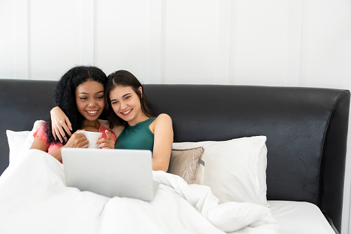 Happy gay couple of women having fun using computer laptop at home