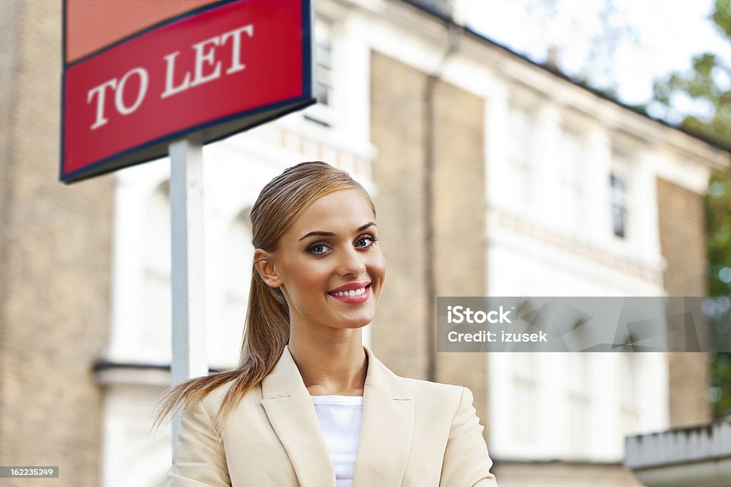 Female Real Estate Agent Outdoor portrait of a female real estate agent standing in front of a property next to To Let Sign and smiling at the camera. 20-24 Years Stock Photo