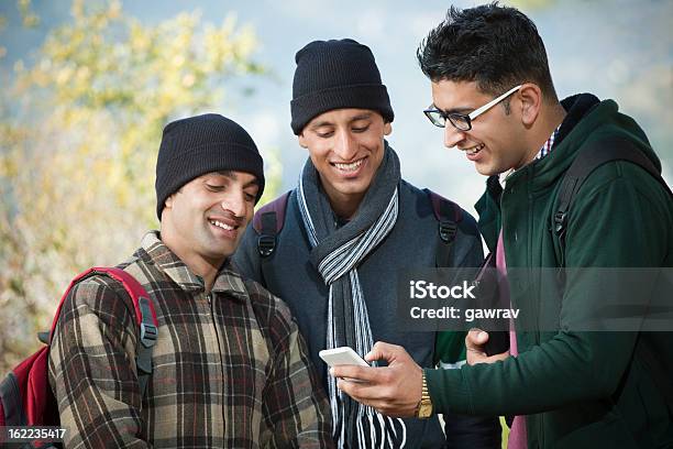 College Student Mostrando Su Nuevo Teléfono Móvil A Amigos Foto de stock y más banco de imágenes de Cultura juvenil