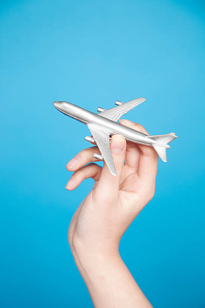 Leaving on a jet plane Woman's hand holding toy airplane, isolated on blue background toy airplane stock pictures, royalty-free photos & images