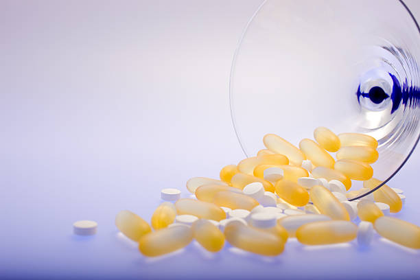 martini-glas mit spilled details - capsule gel effect pill vitamin pill stock-fotos und bilder