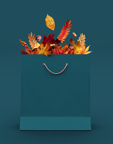 Shopping bag full of colorful autumn leaves on teal background with copy space. 3D Rendering, 3D Illustration