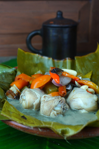 Garang Asem, the traditional Javanese food is served on a clay plate, lined with banana leaves and accompanied by a mixture of bird eye chili, tomatoes, shallots, garlic, sour starfruit, and various other spices. Popular food in Indonesia.
