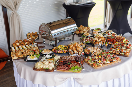 Warming tray with food and people in the background. Party lunch or dinner concept.
