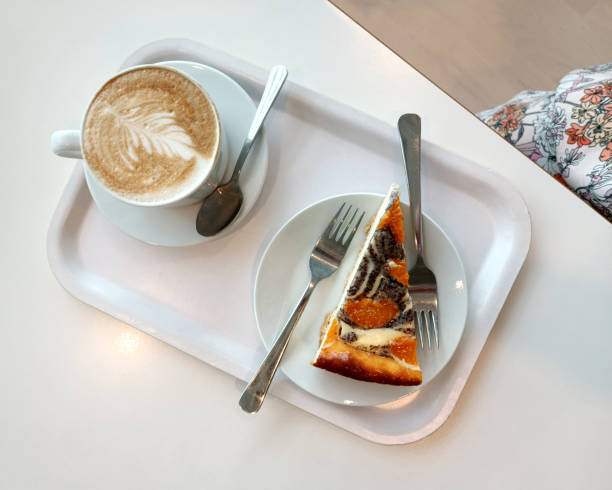 istock mug of cappucci with a pattern and a piece of cake on a white tray on a table 1622455782