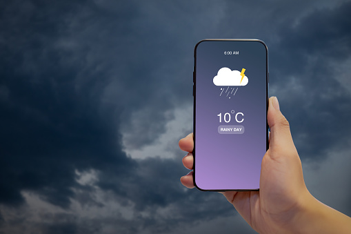 Hand holding Smartphone for check Weather rainy day information show on screen. Weather Information. Rainy day concept.