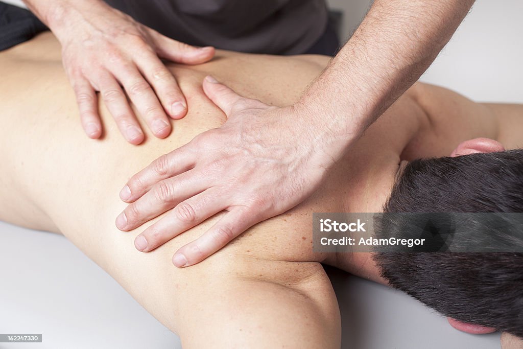 Back massage given to a young man Massage therapist giving a back massage Activity Stock Photo