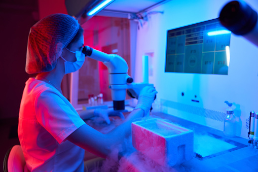 Young embryologist at work in a cryo-laboratory, on the table a tank with liquid nitrogen