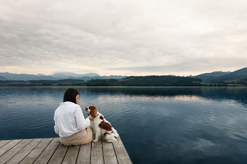 Young woman sitting by the lake with her dog