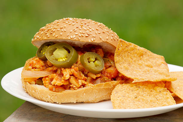 Turkey burger with gherkin on seeded bun. Ground turkey sloppy joe burger on sesame seed bun with corn chips. sloppy joes stock pictures, royalty-free photos & images