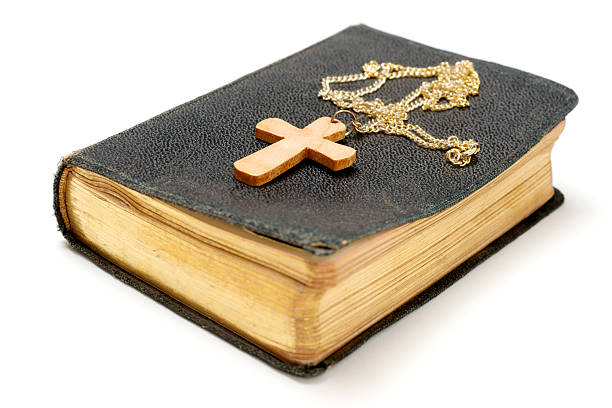 Wooden crose and chain on old bible, isolated on white background.