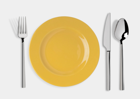 Empty yellow plate and fork,spoon and table knife isolated on white background. Include clipping path.
