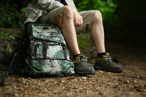 istock Unrecognizable man with backpack sitting on rocks resting during hiking in green forest. Traveling, trekking and adventure concept. 1622556574