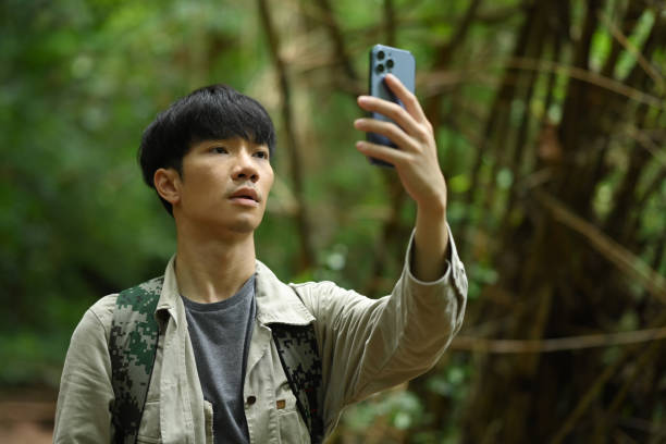 istock Male explorer looking for connection to the internet or using gps navigator app on smartphone in green forest 1622557154
