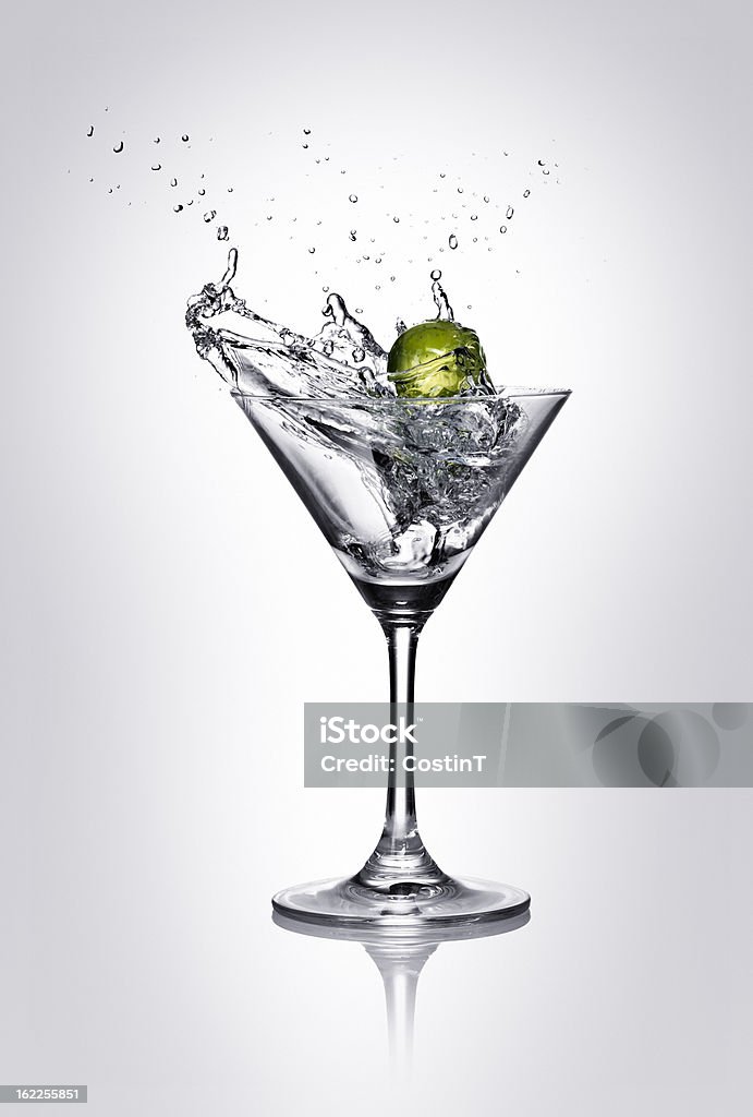 Splash Lime wedge splashing into martini glass. Gray background. Martini Stock Photo