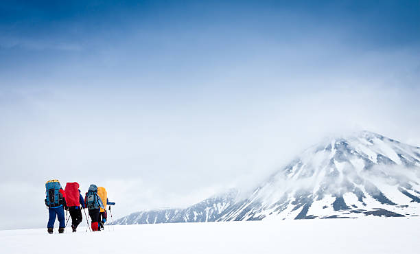 Group with gear and backpacks crossing icy field to mountain