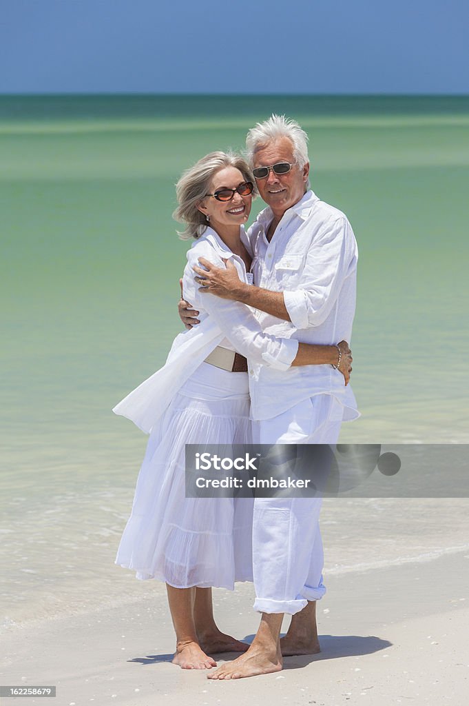 Felice coppia Senior abbracciare sulla spiaggia tropicale - Foto stock royalty-free di Abbracciare una persona