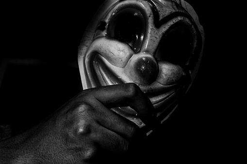 A creepy clown figure in the dark.