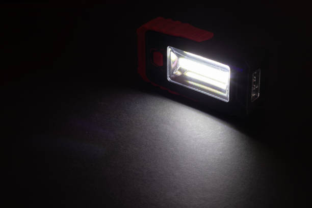istock Flashlight and a beam of light in darkness. A modern led lamp with bright projection on dark wood table. 1622649476