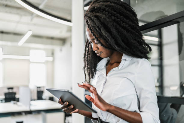 istock Beautiful black woman using digital tablet for communication and project work in modern office 1622649483