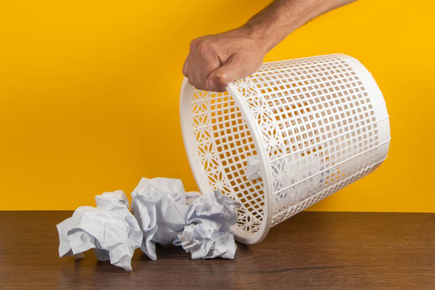 istock Overturned trash can with crumpled paper balls on a yellow background 1622651631