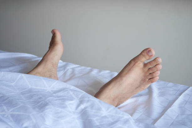 young Woman lying with bare feet in bed