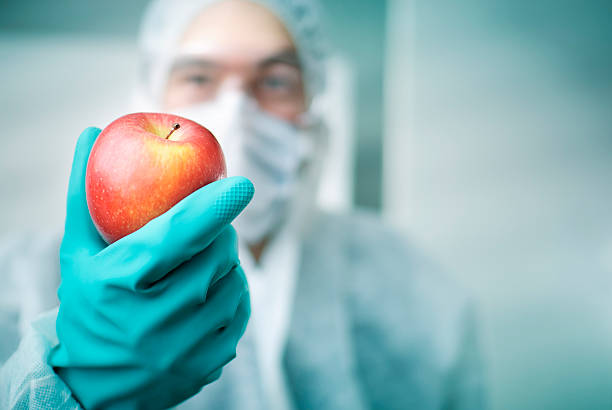 Lab Worker Holding Apple A lab worker holding an apple  genetically modified food stock pictures, royalty-free photos & images