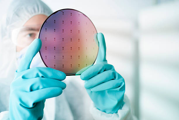 Silicon Wafer Lab worker examining a silicon wafer cleanroom photos stock pictures, royalty-free photos & images