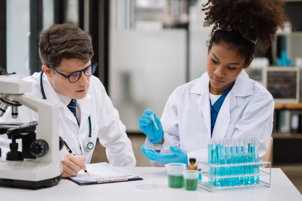 istock Team of biochemical research scientists working with a microscope for vaccine development in pharmaceutical research labeling. 1622680248