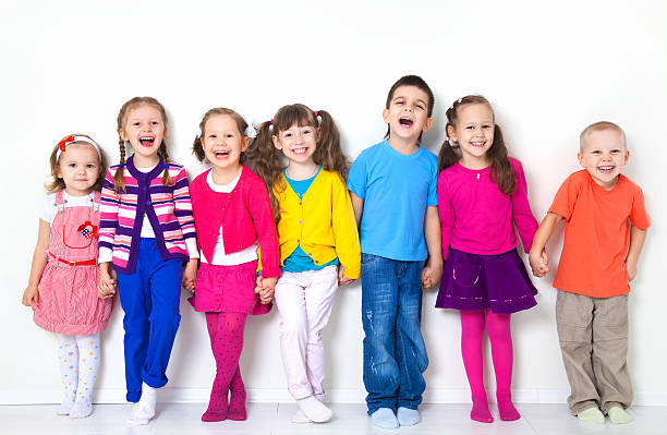 A group of children standing against a wall stock photo