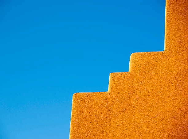Southwestern Adobe wall and blue sky Part of an Adobe skyle house and blue sky. Taken at Albuquerque and Santa Fe area, in New Mexico, USA. adobe material stock pictures, royalty-free photos & images
