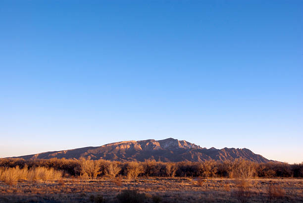View of Taos Sangre de Cristo mountains view from Ranchos de Taos valley and green landscape in summer with clouds