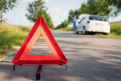 This image features an emergency triangle sign, a symbol of roadside safety, placed on the road to alert drivers