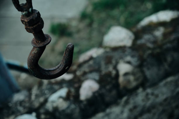 istock Rusty old hook on a chain over a stone well surrounded by stained glass windows and green plants 1622736881