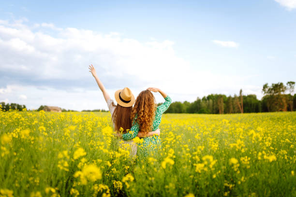 istock Two cheerful girlfriends dressed in stylish dresses are walking through a blooming rapeseed field 1622742101